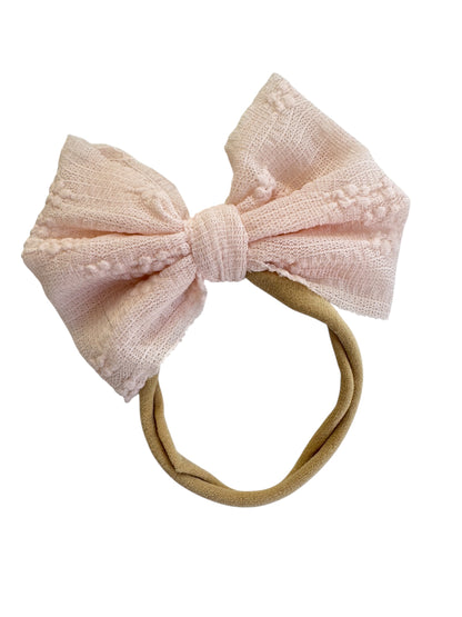 Pink textured bow headband on a white background