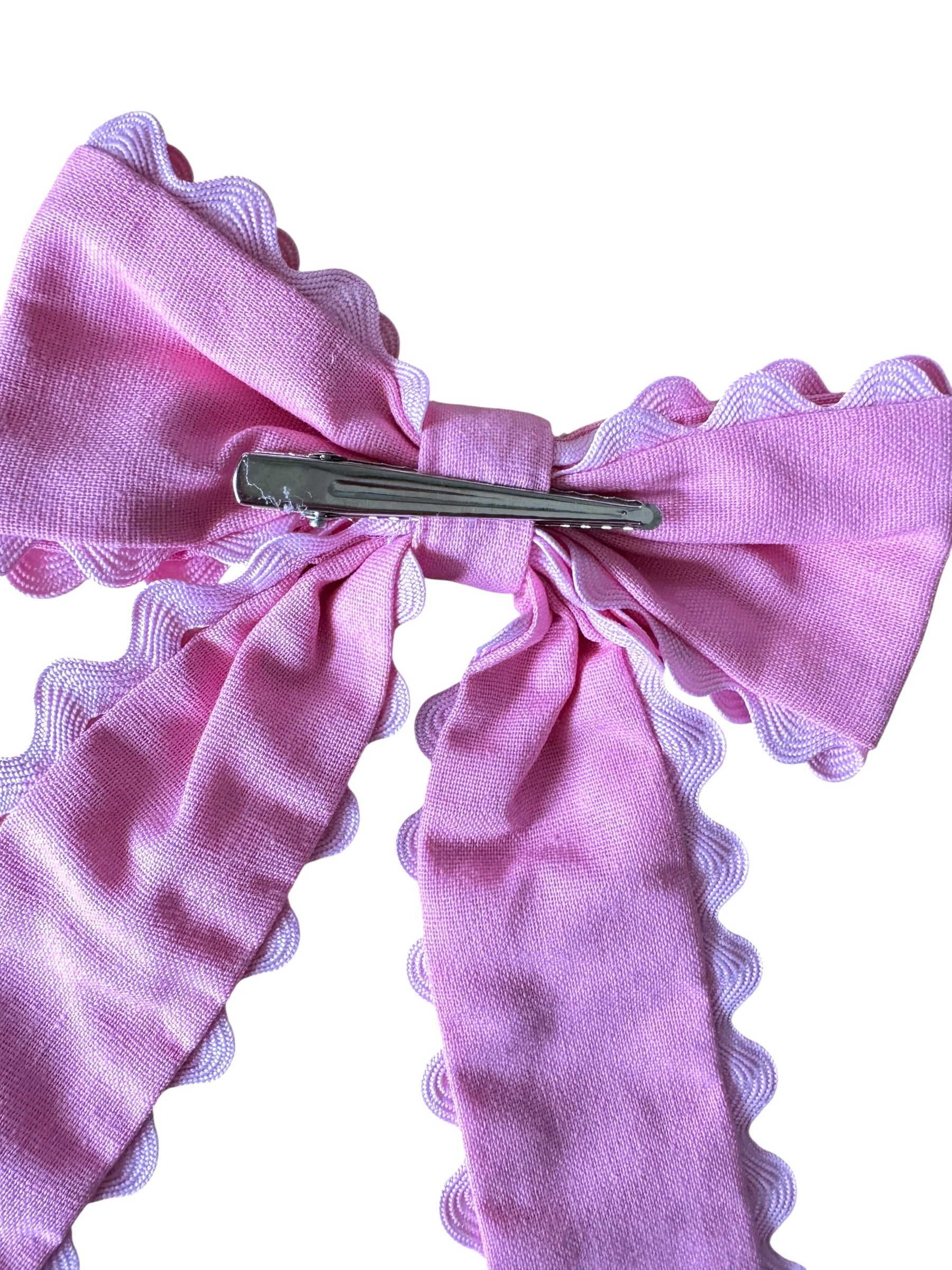Pink bow hair clip with scalloped edges on a white background