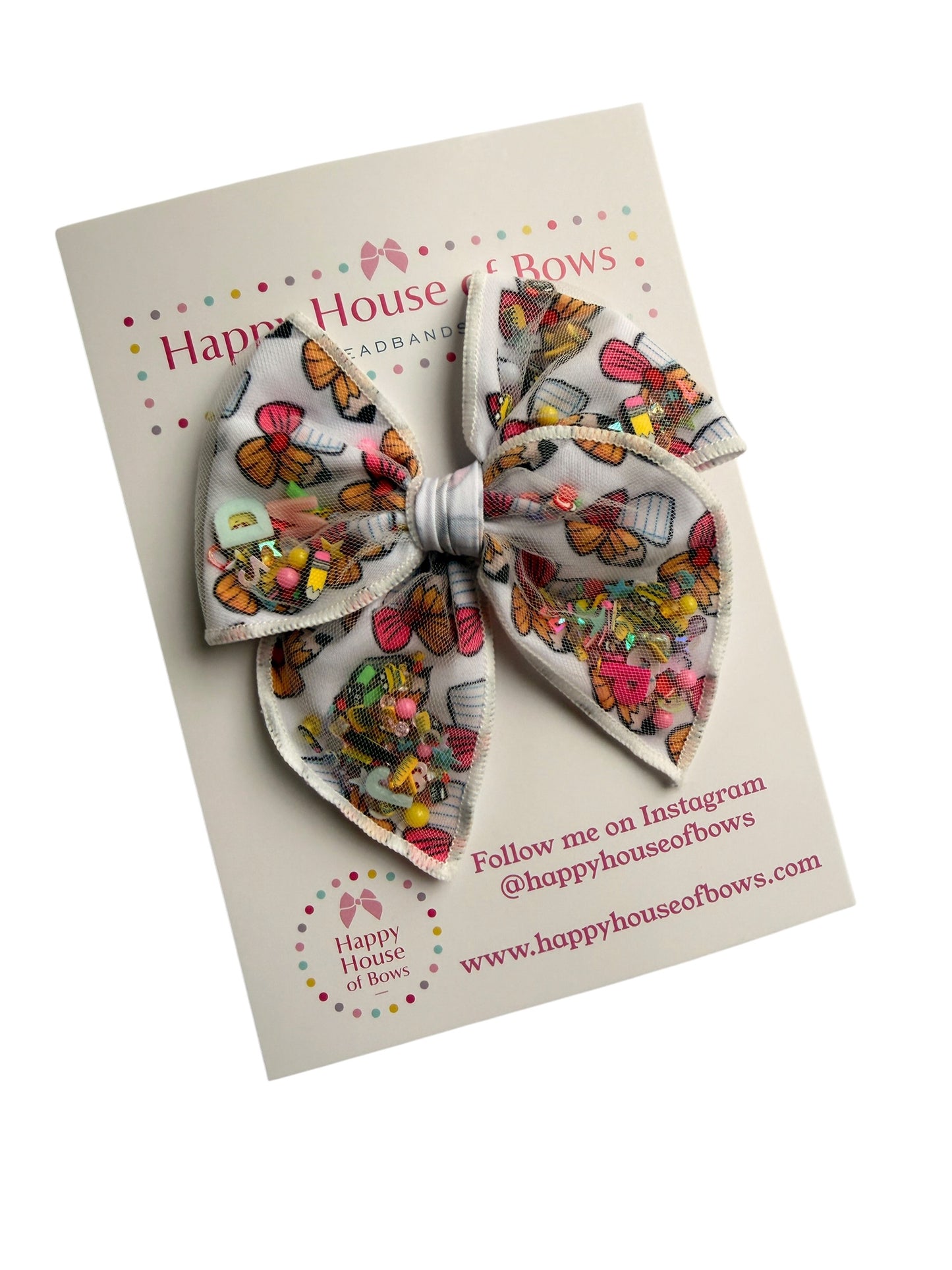 A double-layered fabric hair bow with a colorful vintage postcard print, presented on its original white backing card from Happy House of Bowz.