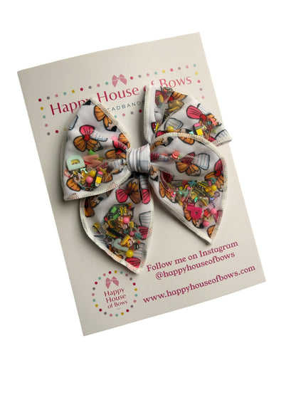 A double-layered fabric hair bow with a colorful vintage postcard print, presented on its original white backing card from Happy House of Bowz.