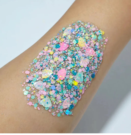 Pastel glitter applied to a person's arm against a hair and body gel light background