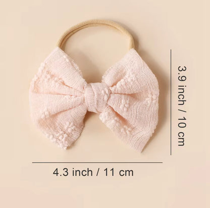 Pink knitted bow headband with measurements on a beige background