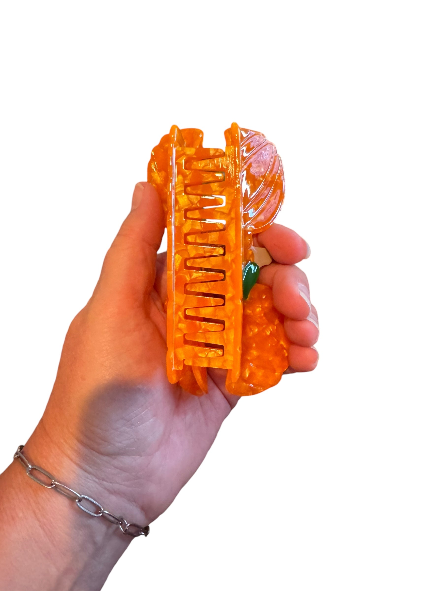 An orange pumpkin-shaped Halloween mouse ear claw clip against a white background
