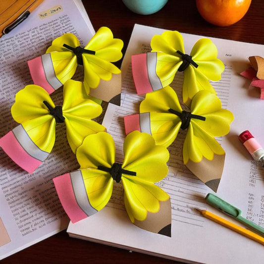 Yellow pencil hair clips on a book with stationery items.