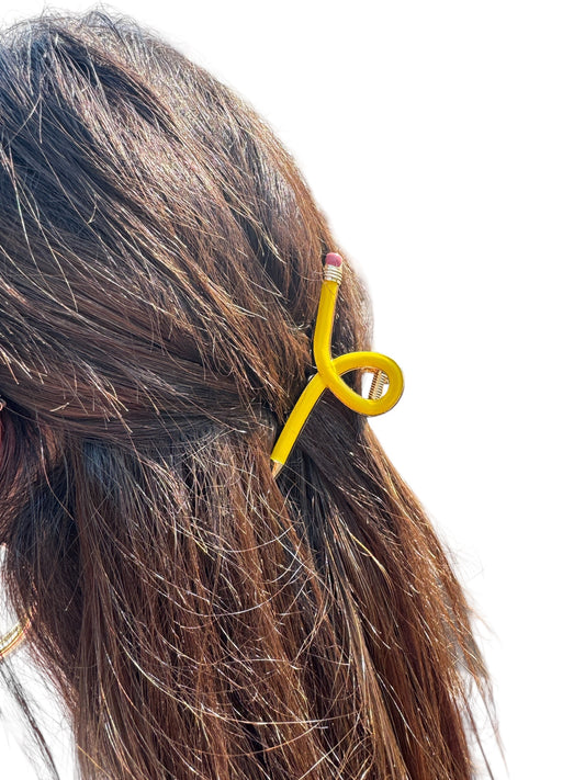Yellow pencil hair clip in a person's hair on a white background