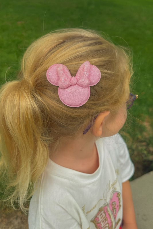 Child with pink Minnie Mouse hair clip outdoors