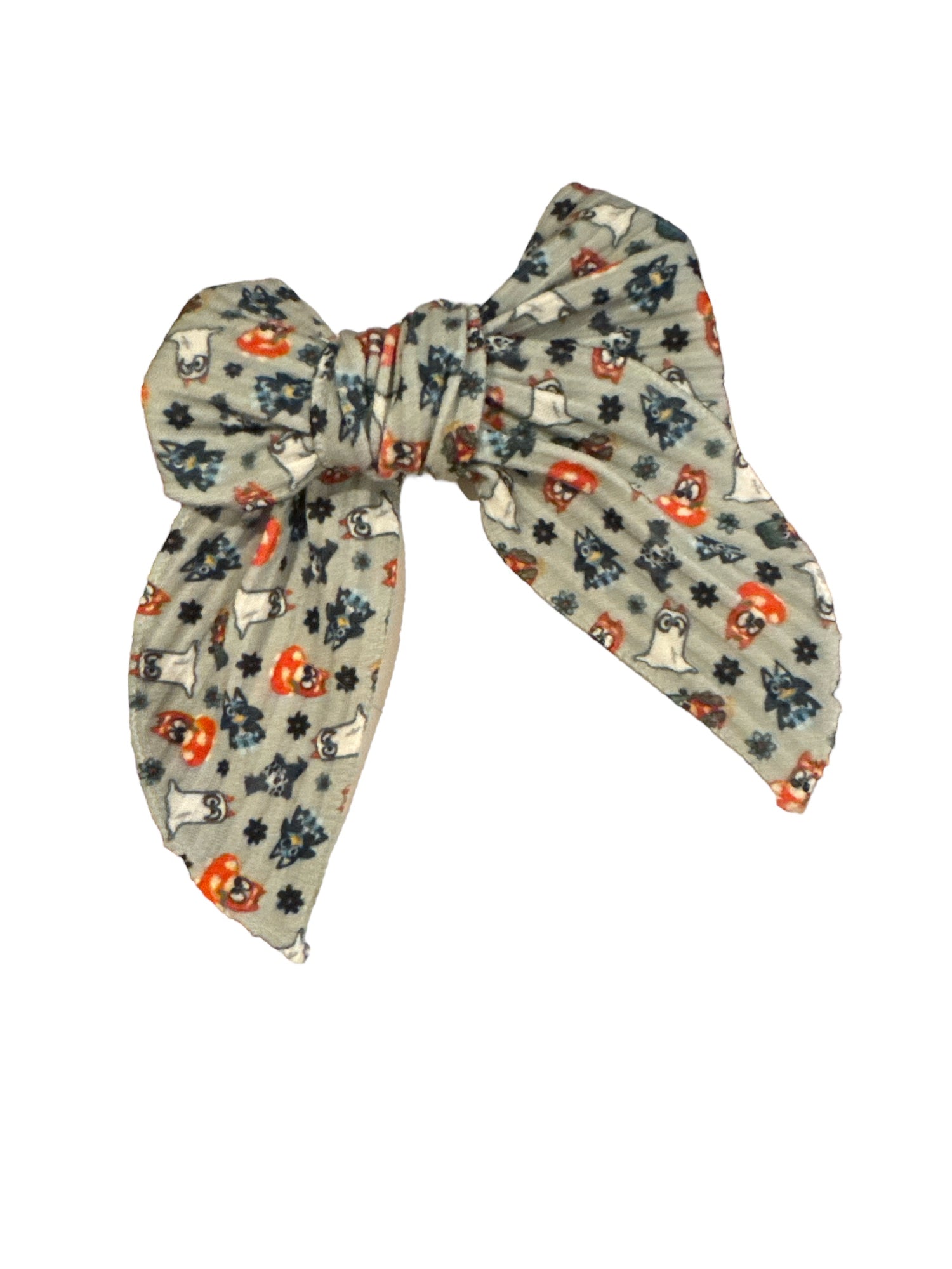A hair bow with a blue dog pattern and Halloween motifs, attached to an alligator clip.