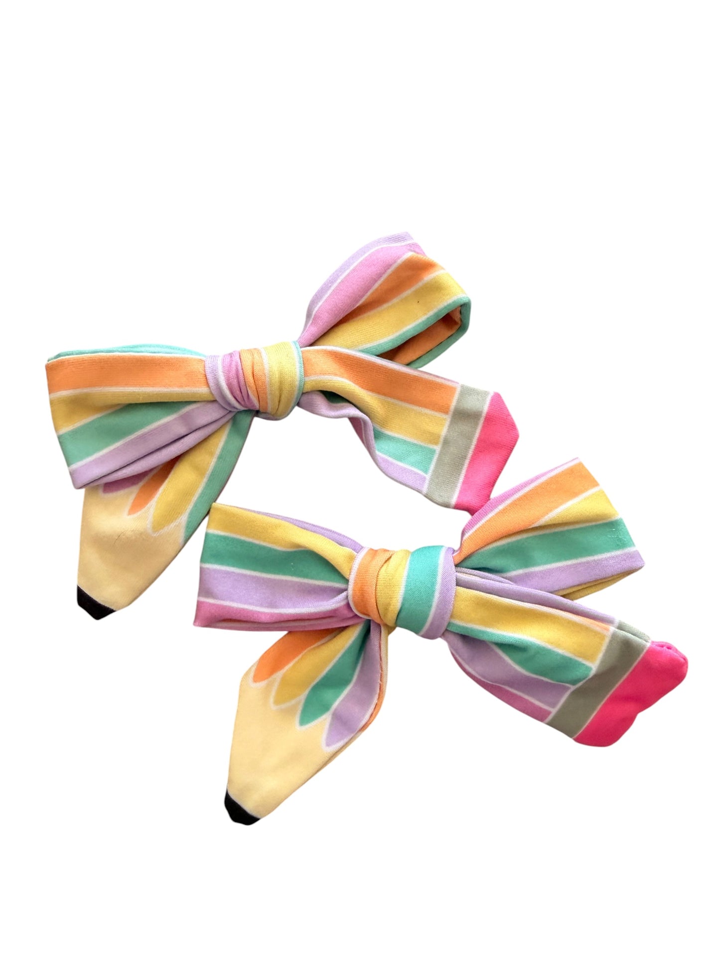 Two pastel rainbow striped fabric hair bows on a plain white background.