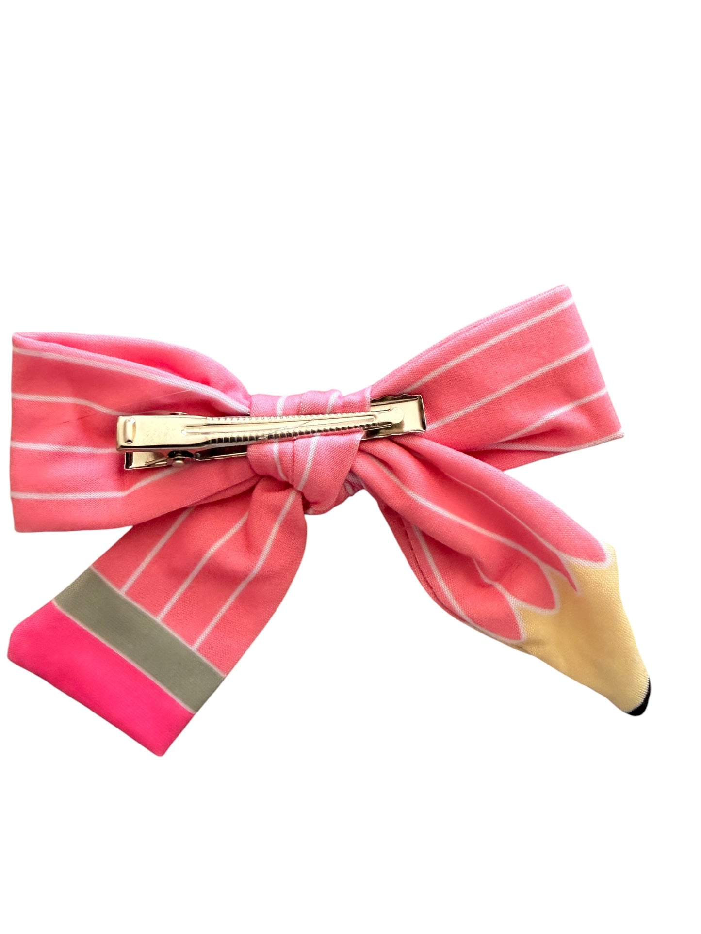 A pink hair bow accessory featuring a pencil design, with a gold metal clip at the center, on a plain white background.