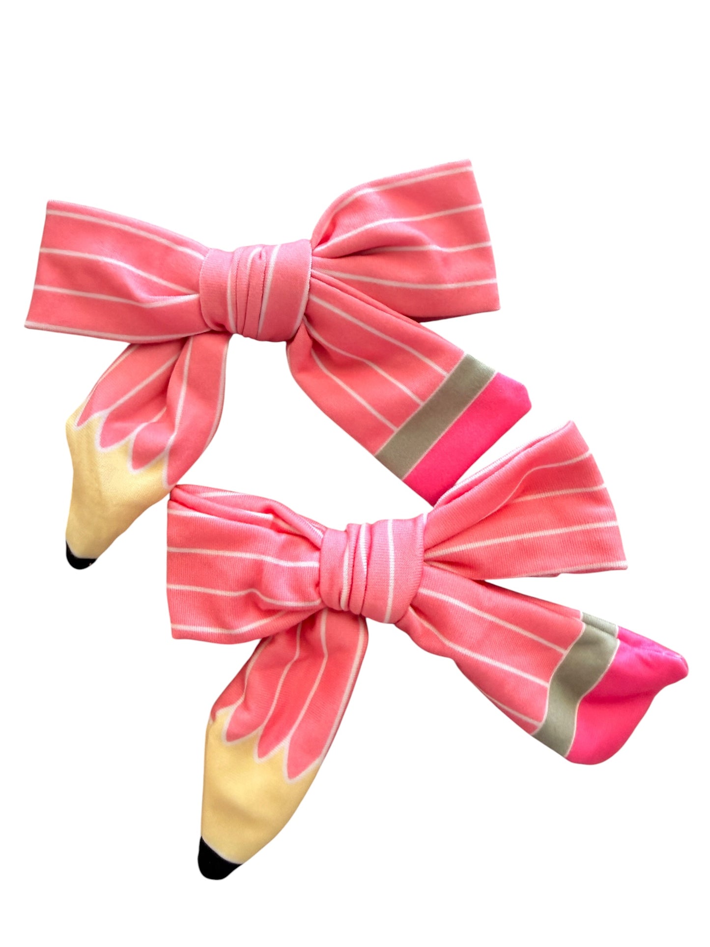 Two pink striped fabric hair bows designed to look like pencils, with yellow erasers and gray graphite accents, shown on a plain white background.