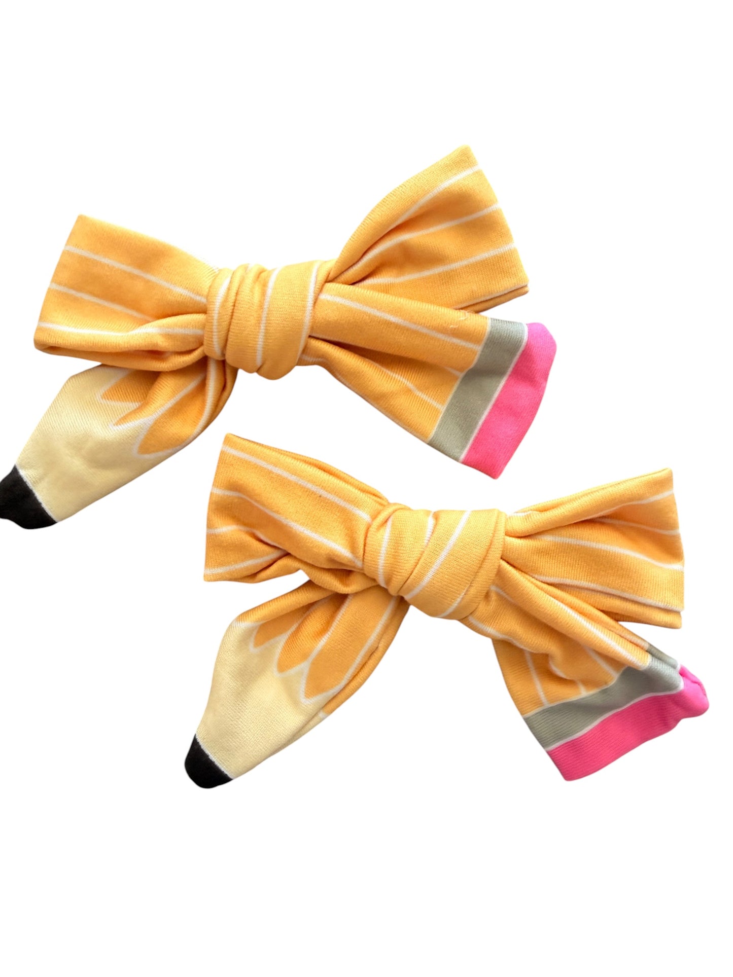 Two yellow pencil-shaped hair bows with white stripes, pink eraser ends, gray graphite accents, and black tips, displayed on a solid white background.