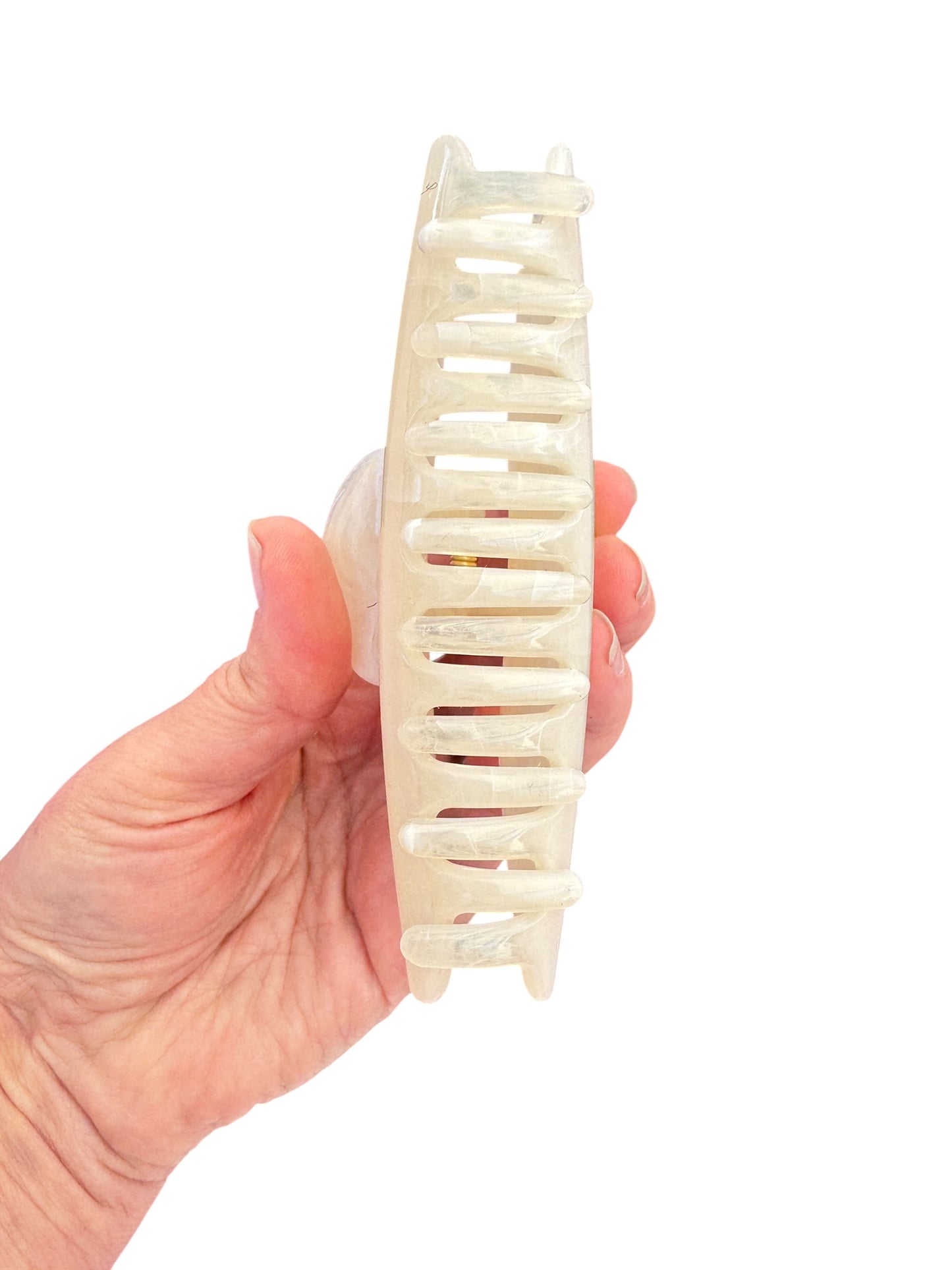 Hand holding a white hair clip against a white background