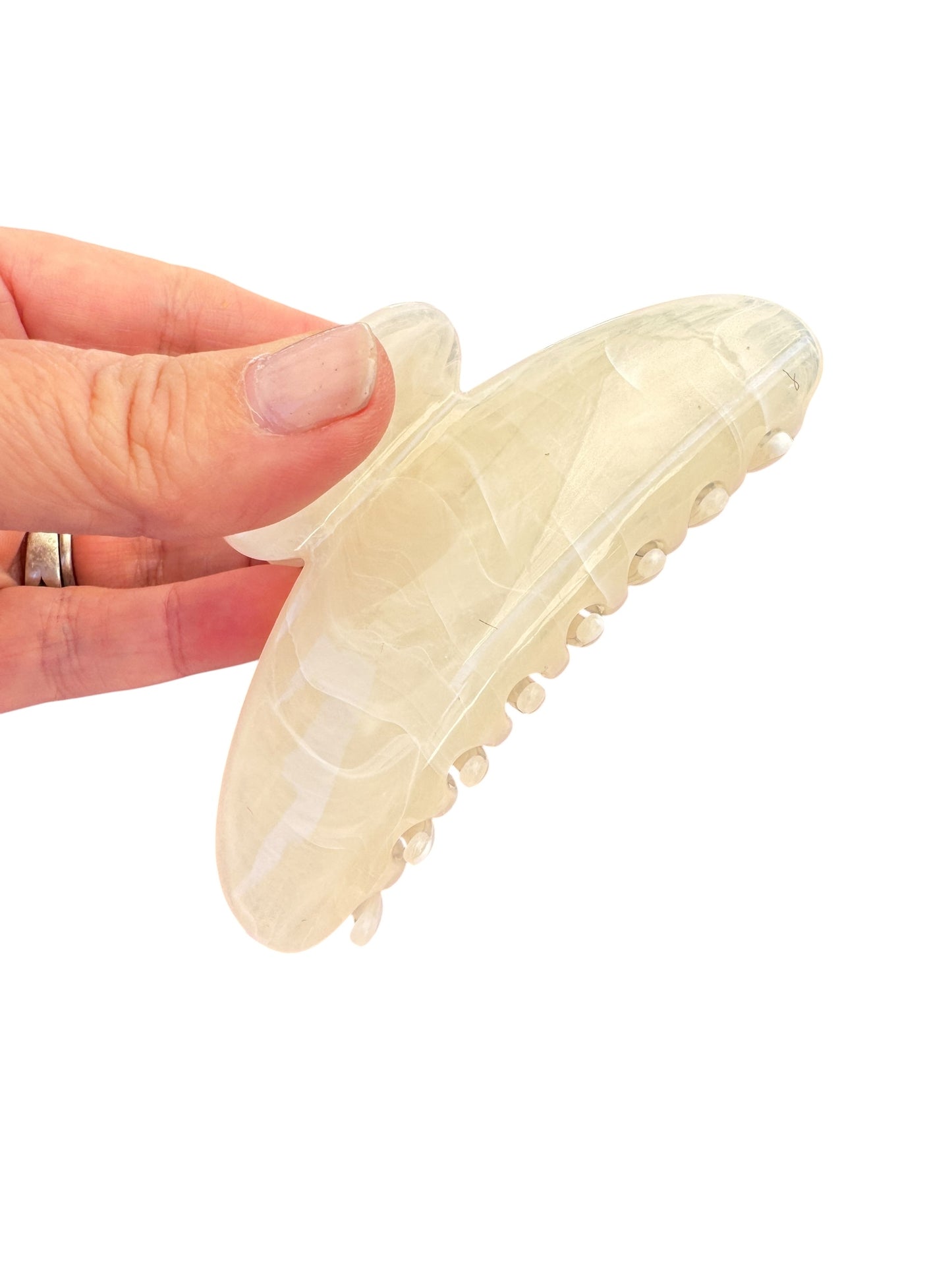 Beige slip-on shoe held by a hand on a white background