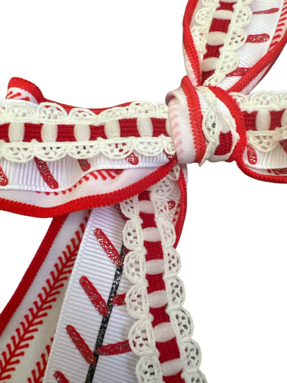 Close-up of red and white baseball hair bow with lace details on a white background
