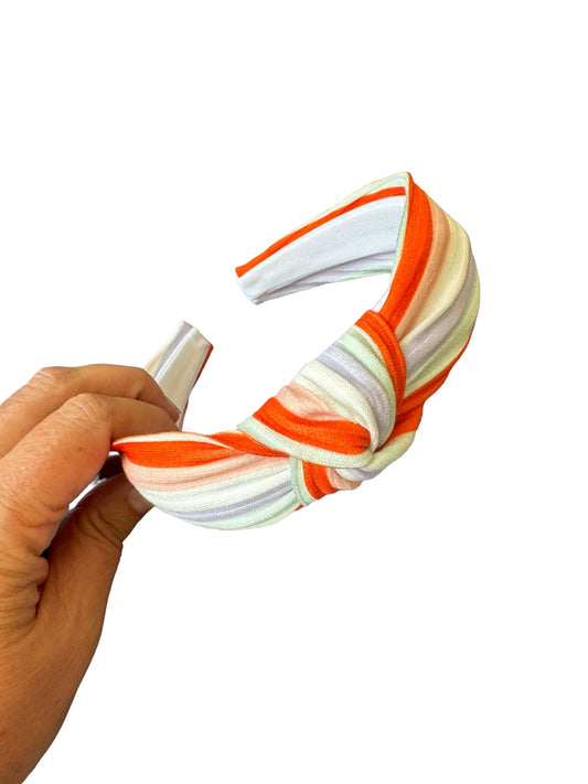 one headband with fall striped patterns, one in orange and the other in purple, displayed on a white surface with a small white pumpkin in the background.